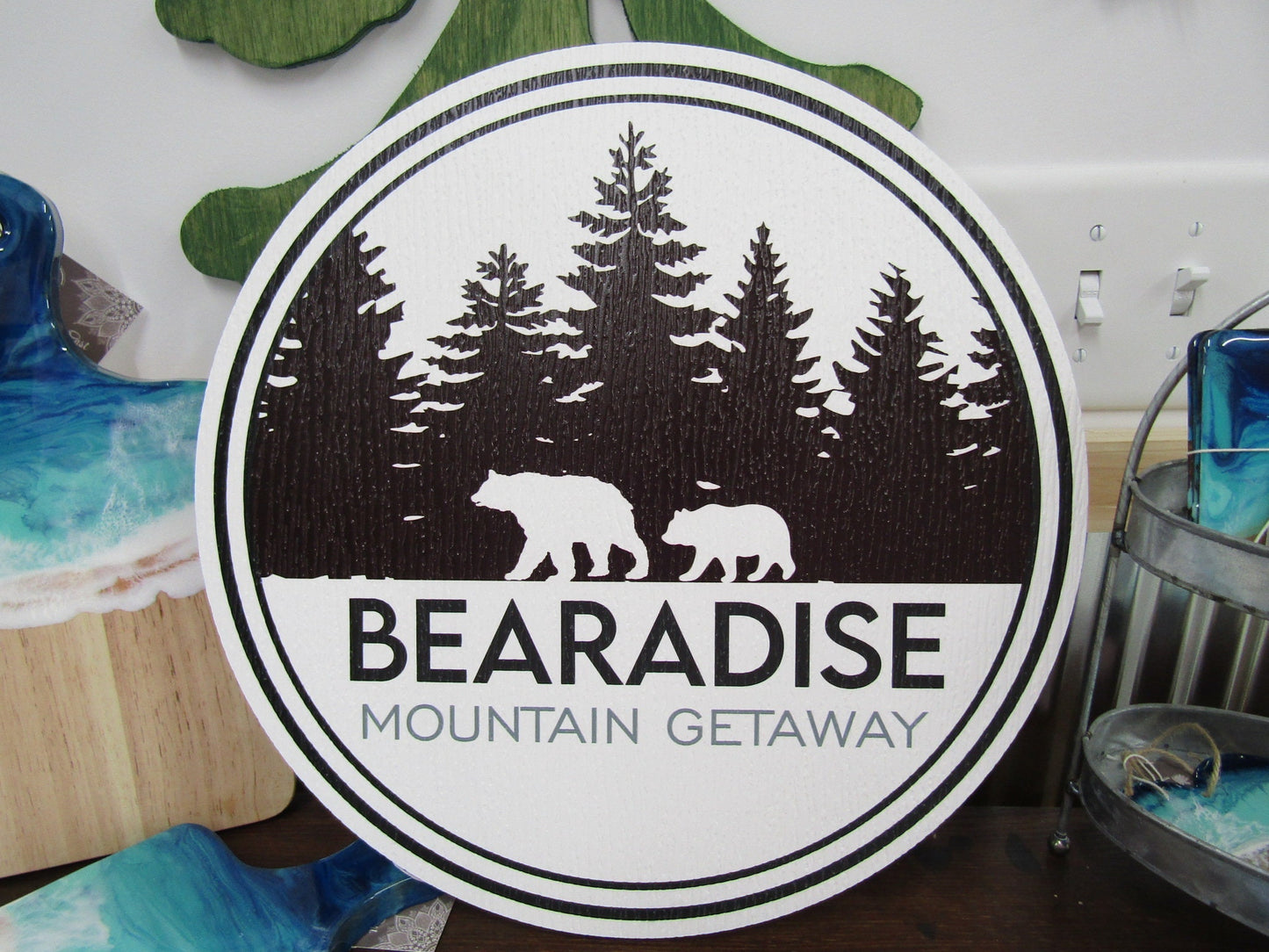 A round sign for Bear's Paradise Mountain Getaway, featuring custom cabin pine trees wilderness bears textured PVC, weather fade resistant, waterproof UV printed color logo business commercial signage