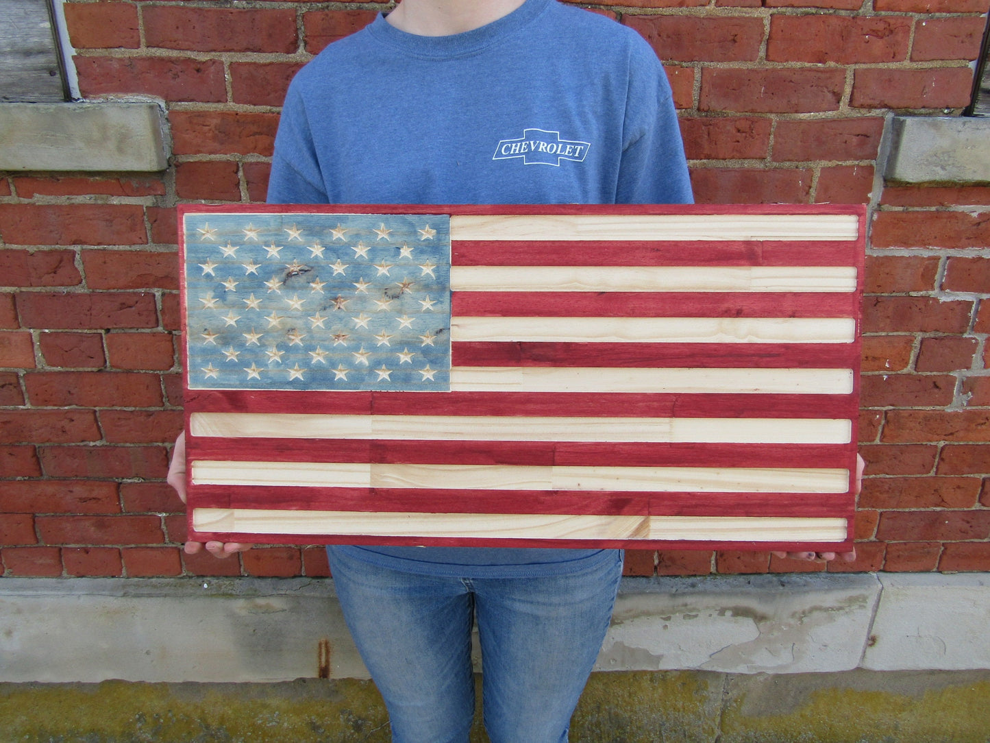 May include: A wooden American flag with red and white stripes and blue stars. The flag is made of individual wood planks.